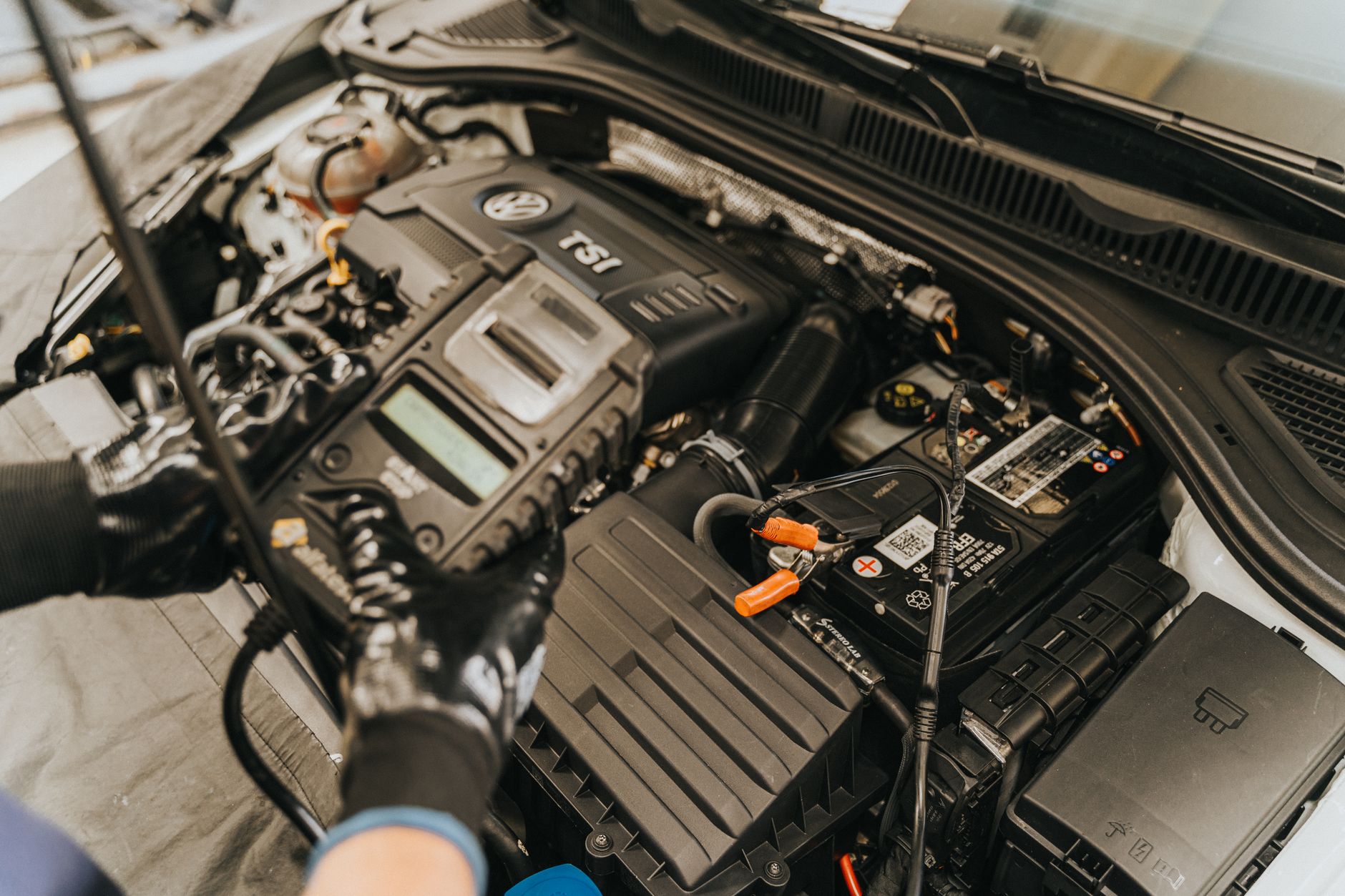 Portable lithium jump starter clamped to car battery terminals