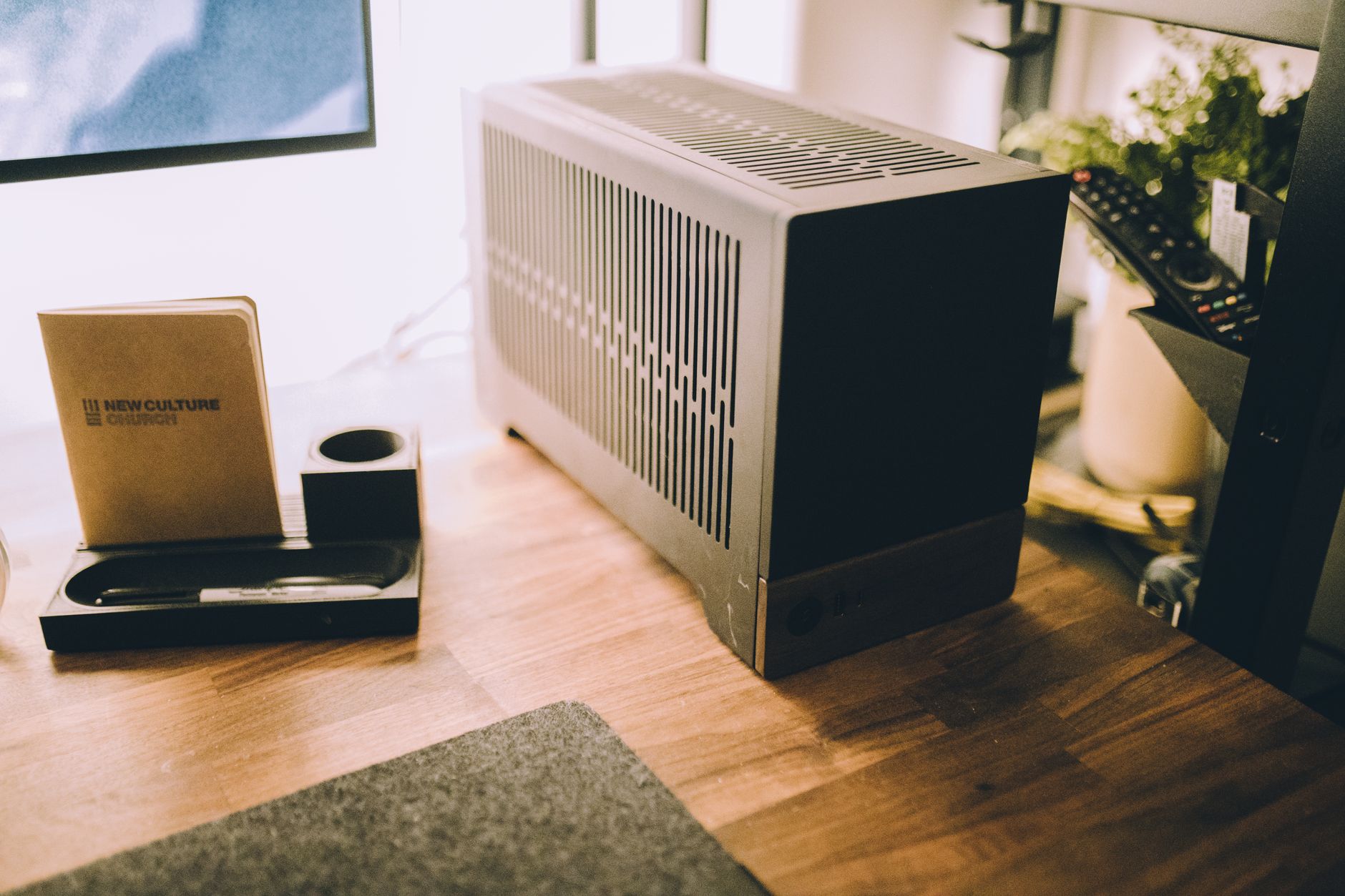 Small black backup battery box and cables sitting on the floor under a wooden desk
