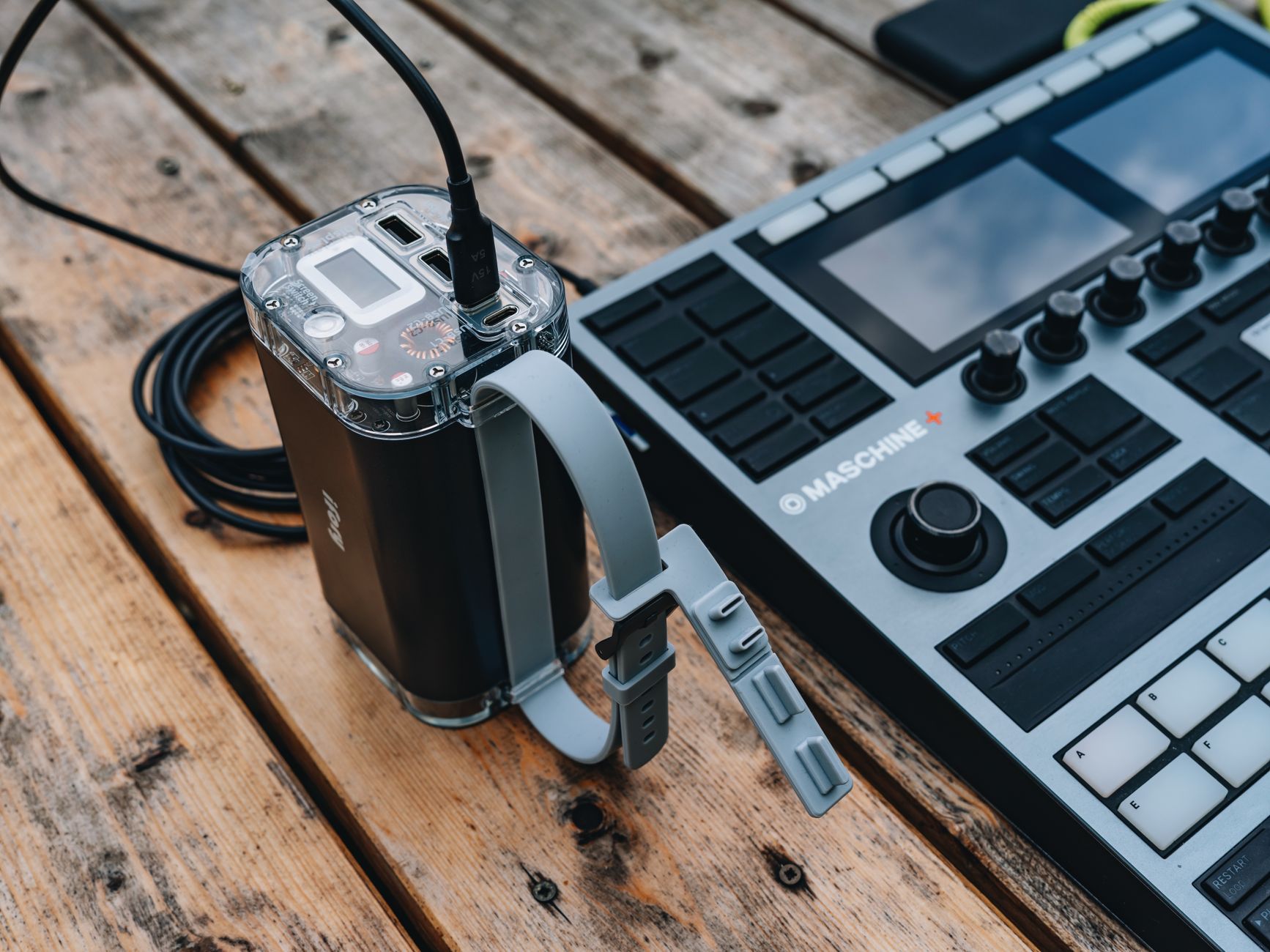 Portable power station sitting on a wooden workbench with charging cables attached
