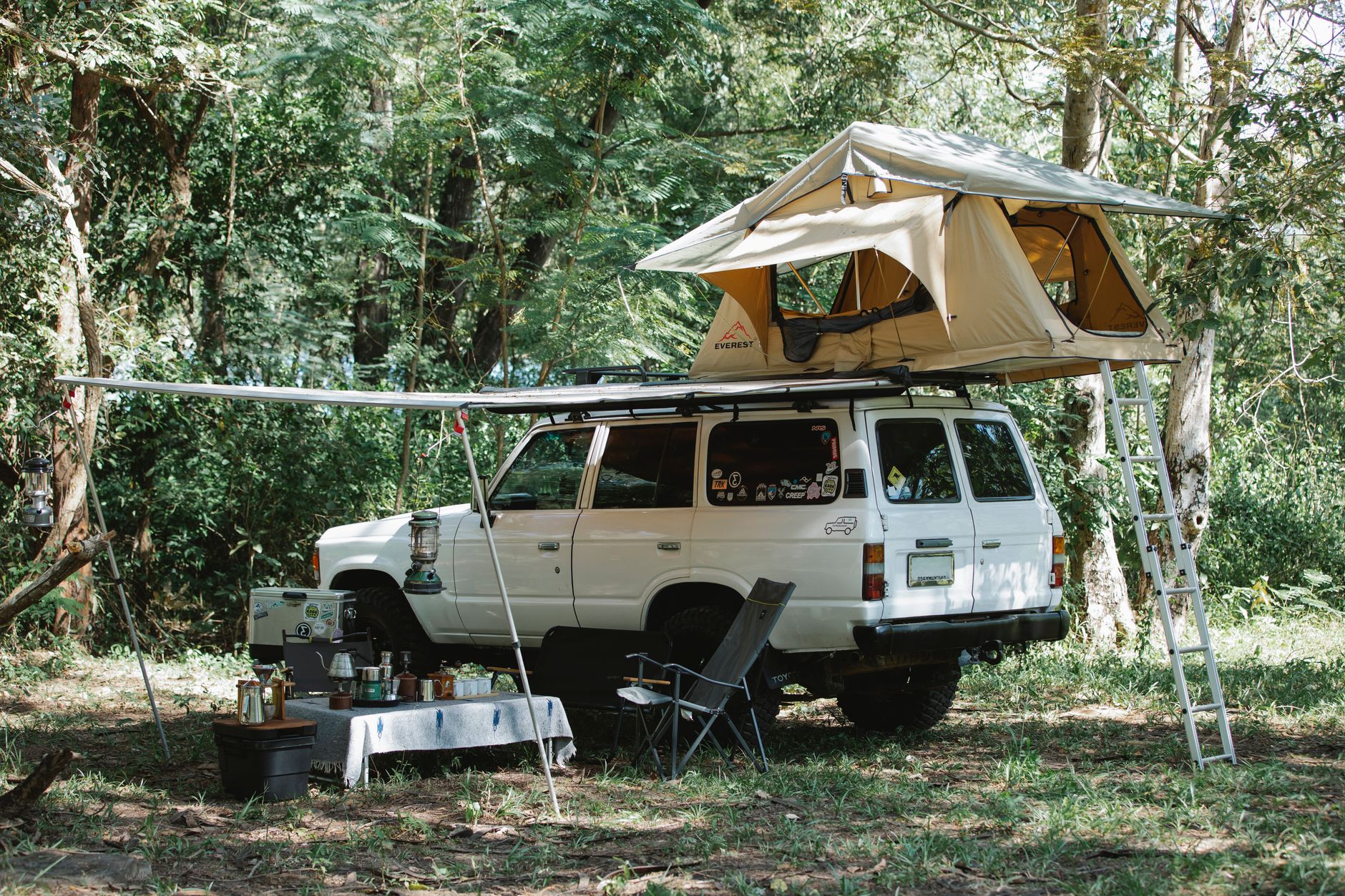 Folding solar panel propped up charging a battery box next to a campsite tent