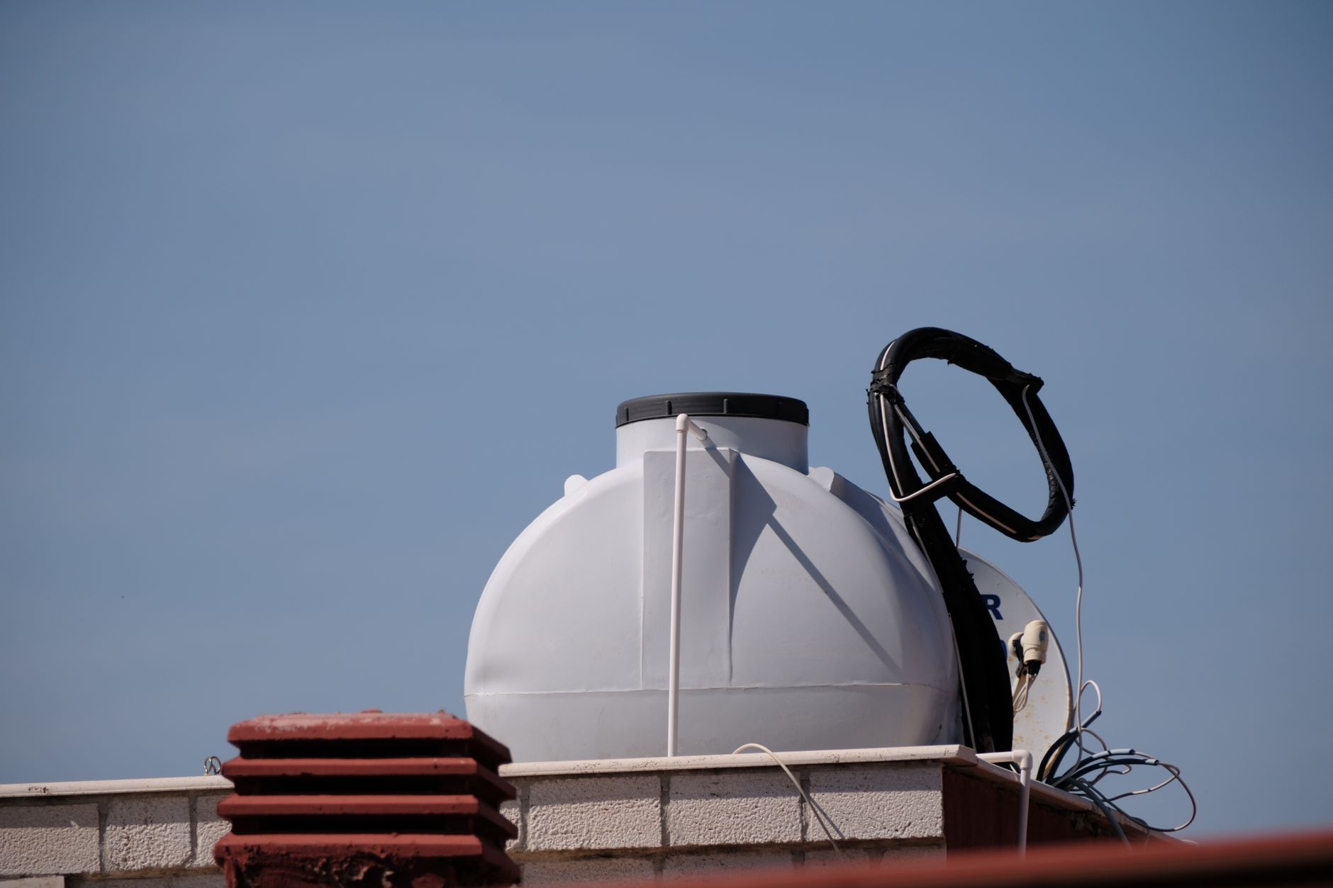 Large white propane tank beside a residential standby generator outside a brick home.