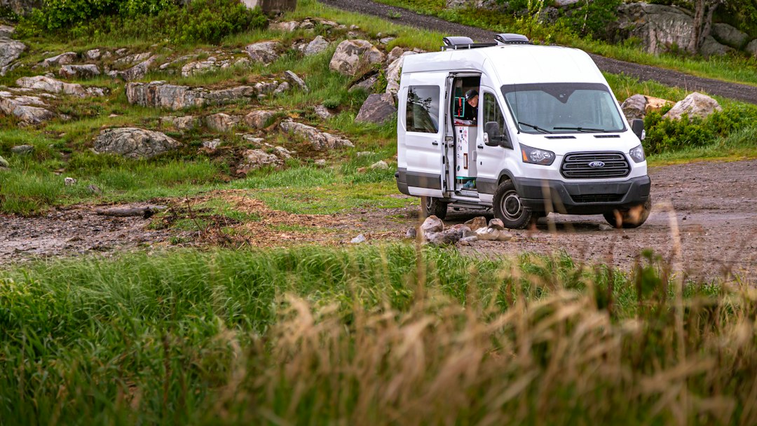 Two campers using a portable power station beside a camper van at dusk